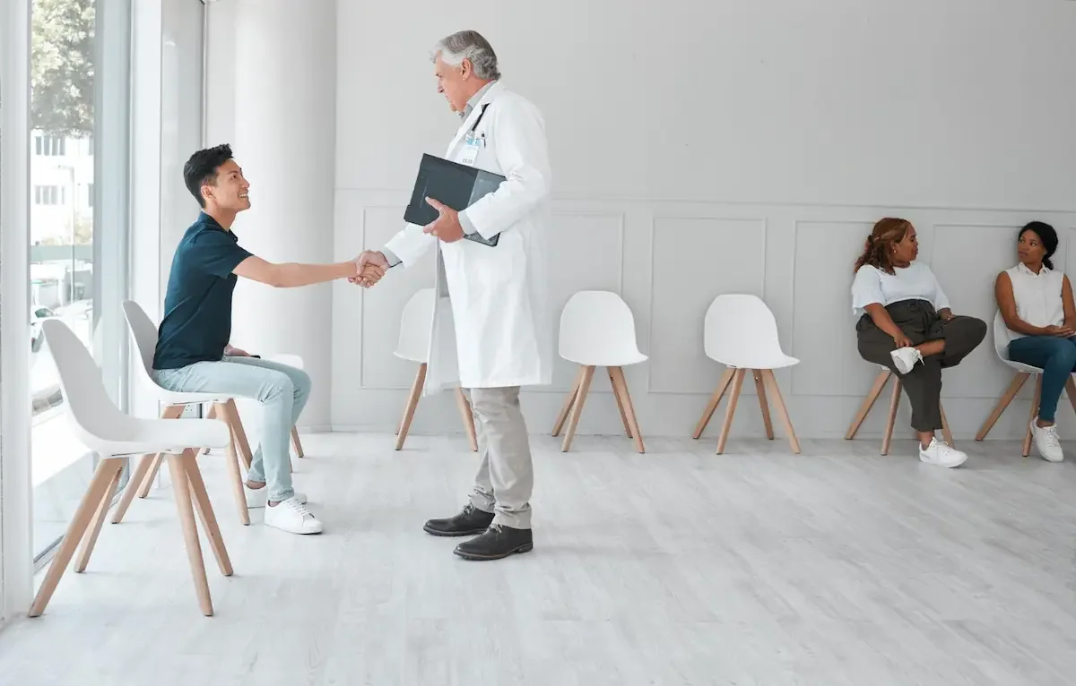 Un praticien accueille un patient dans la salle d’attente d’un cabinet médical