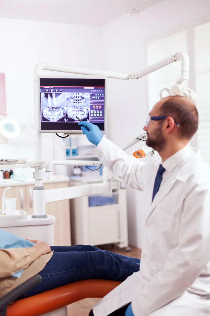 Chirurgien-dentiste qui montre une radiographie numérique sur écran au fauteuil