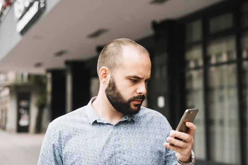 Homme qui se renseigne sur la greffe de cheveux depuis son smartphone