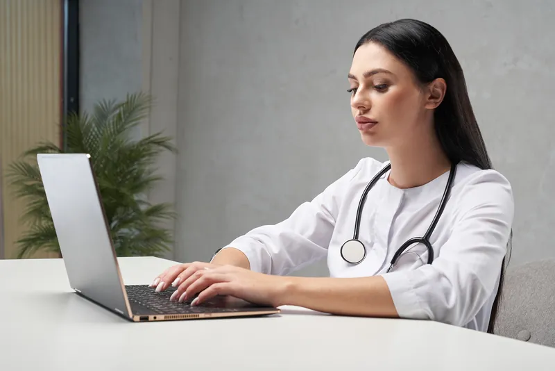 Médecin qui consulte le site internet de son cabinet sur ordinateur portable