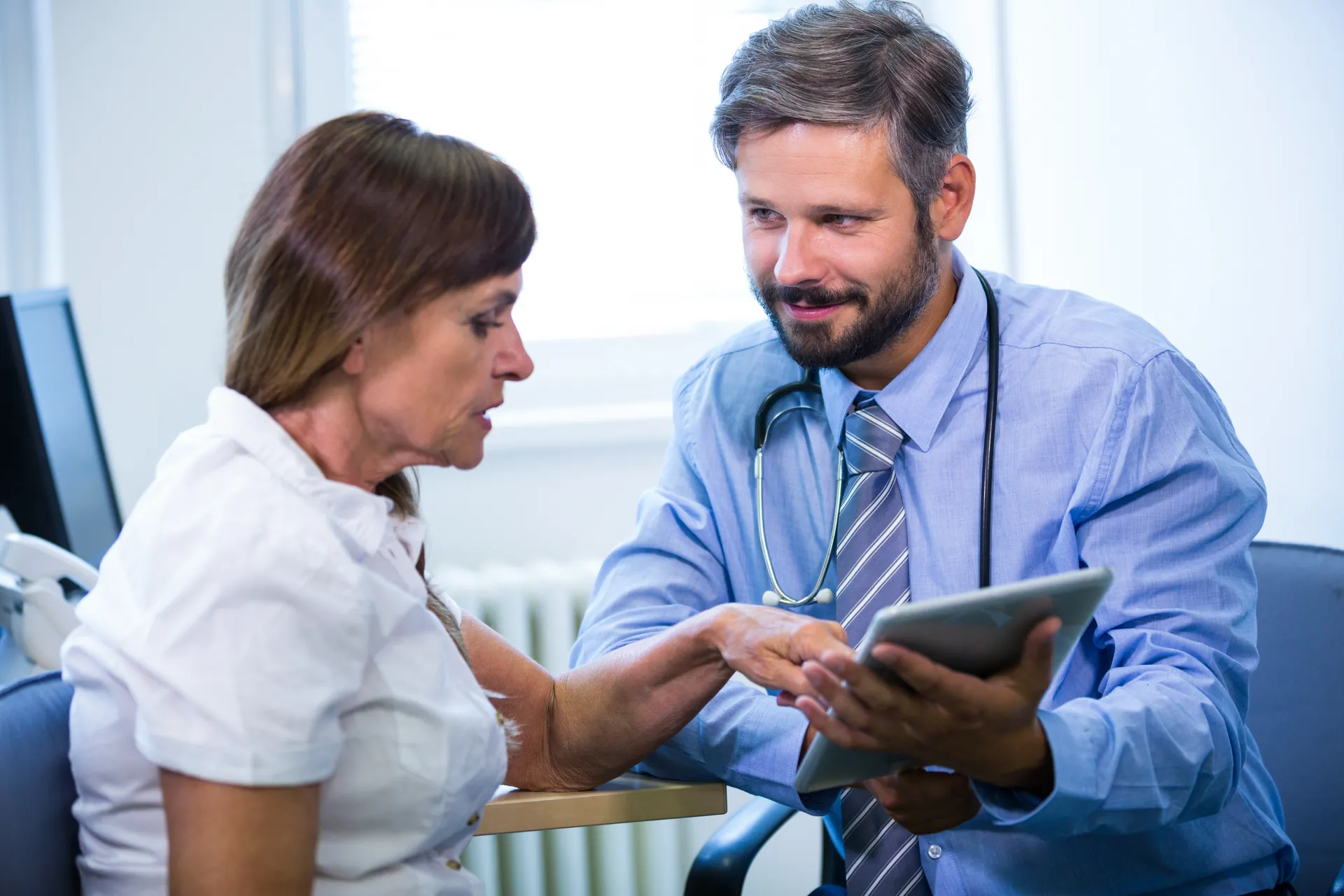 Médecin qui échange avec un patient autour d’une tablette