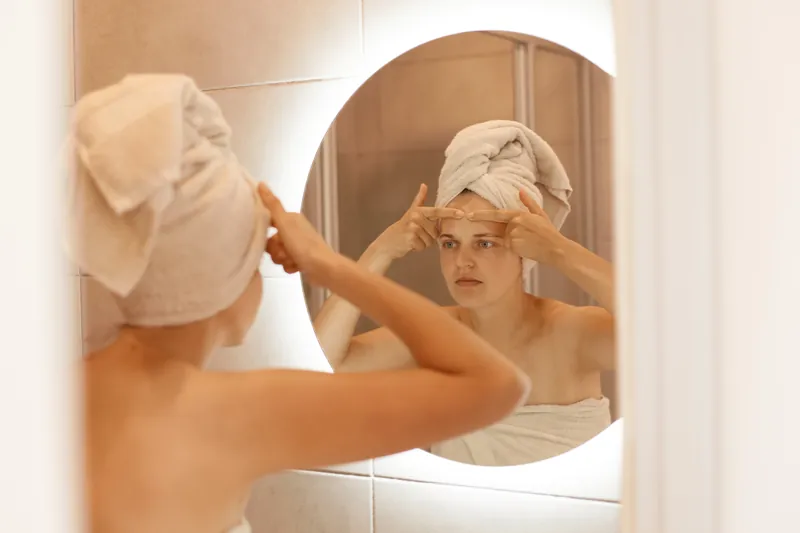 Patiente qui observe sa peau dans le miroir