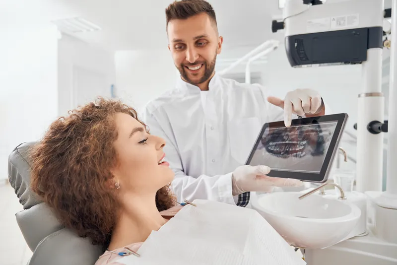 Dentiste qui présente un plan de traitement implantaire sur tablette