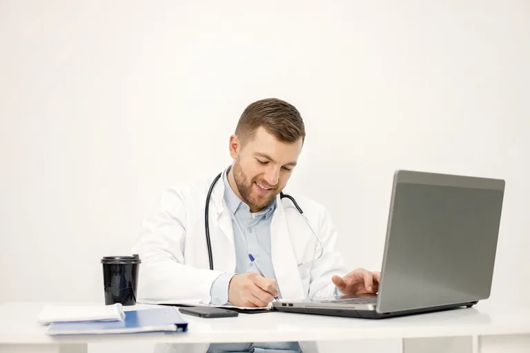 Médecin prenant des notes devant son ordinateur portable