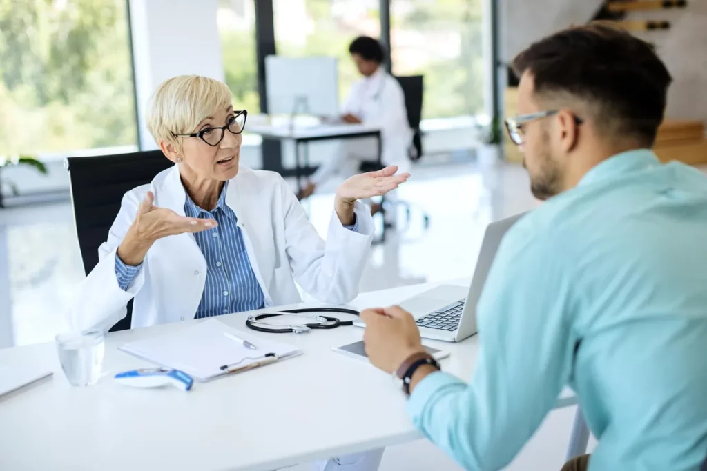 Médecin en consultation expliquant à un patient dans un cabinet lumineux